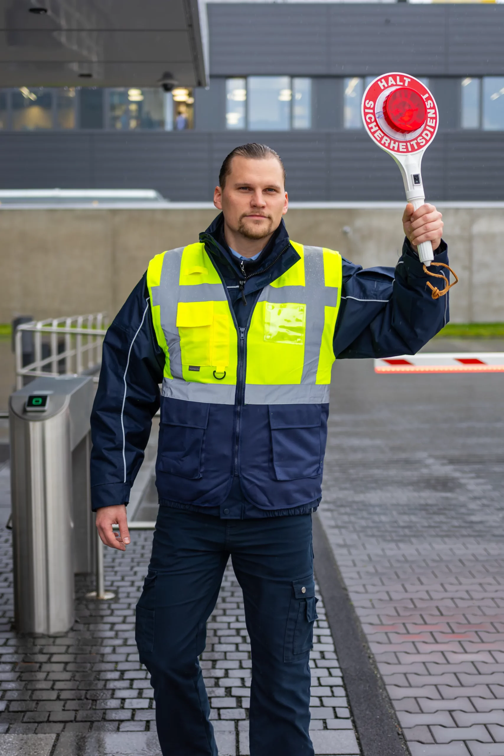 Werkschutzmitarbeiter in gelber Warnweste bei der Zufahrtskontrolle